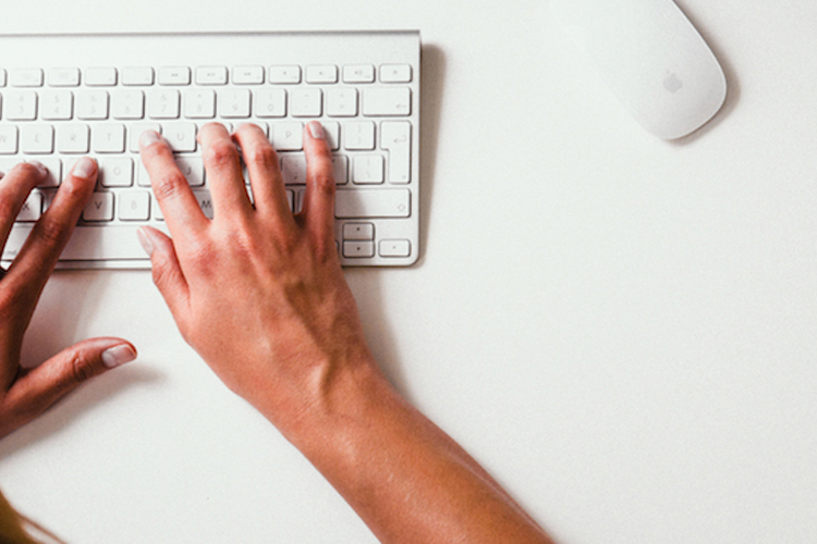 Hands typing on a keyboard with a mouse to the right.
