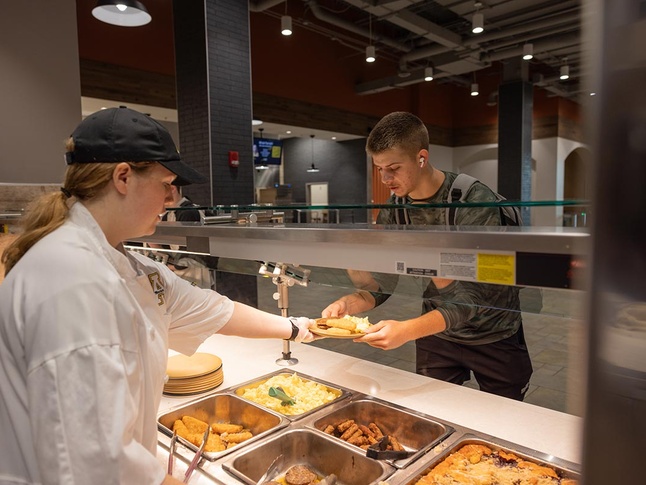 Server handing plate of food to student